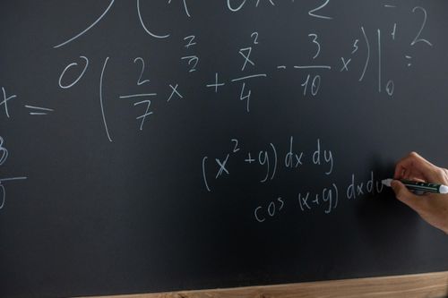 Investment Manger Selection process optimisation depicted by teacher writing equations on chalk board.