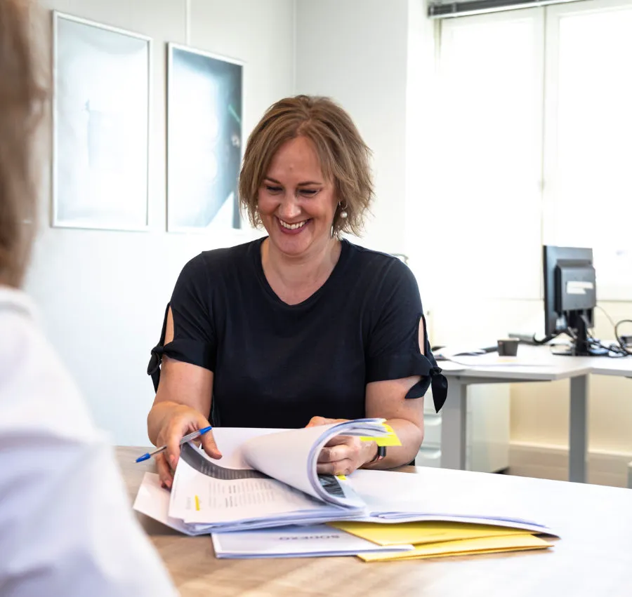 Astrid op haar kantoor die door een boekje bladert