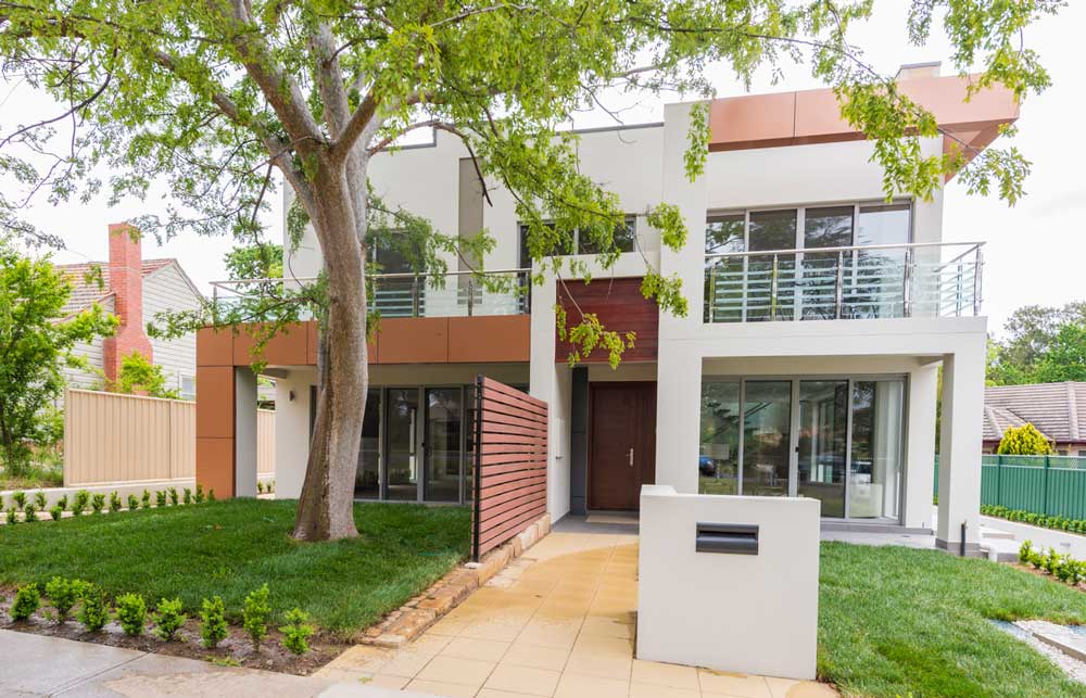A contemporary home with a tree in the front yard.