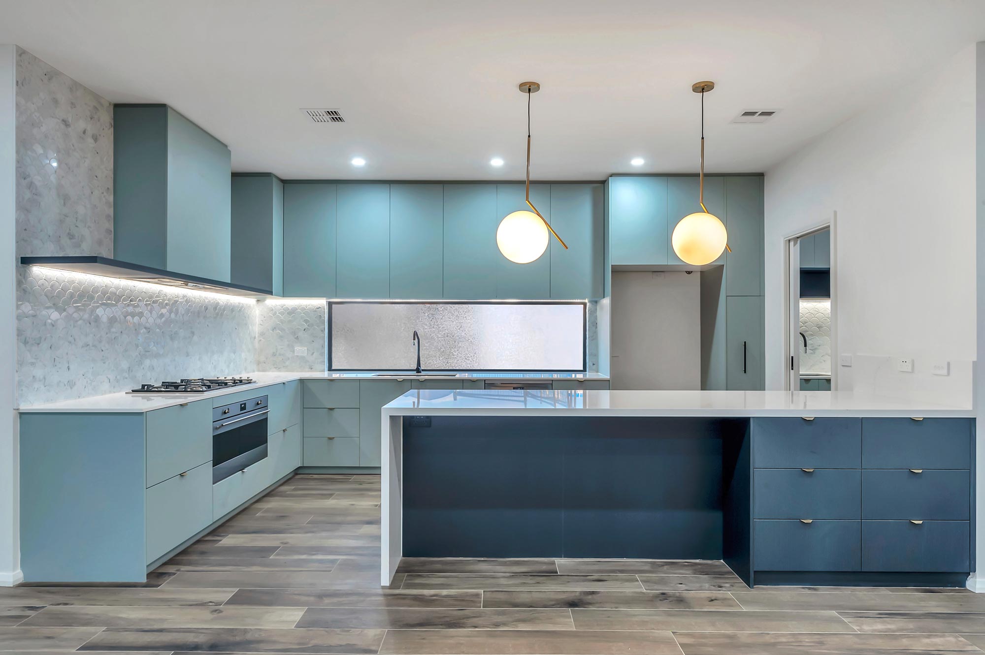 A modern retro kitchen with light blue cabinets and urban lighting.