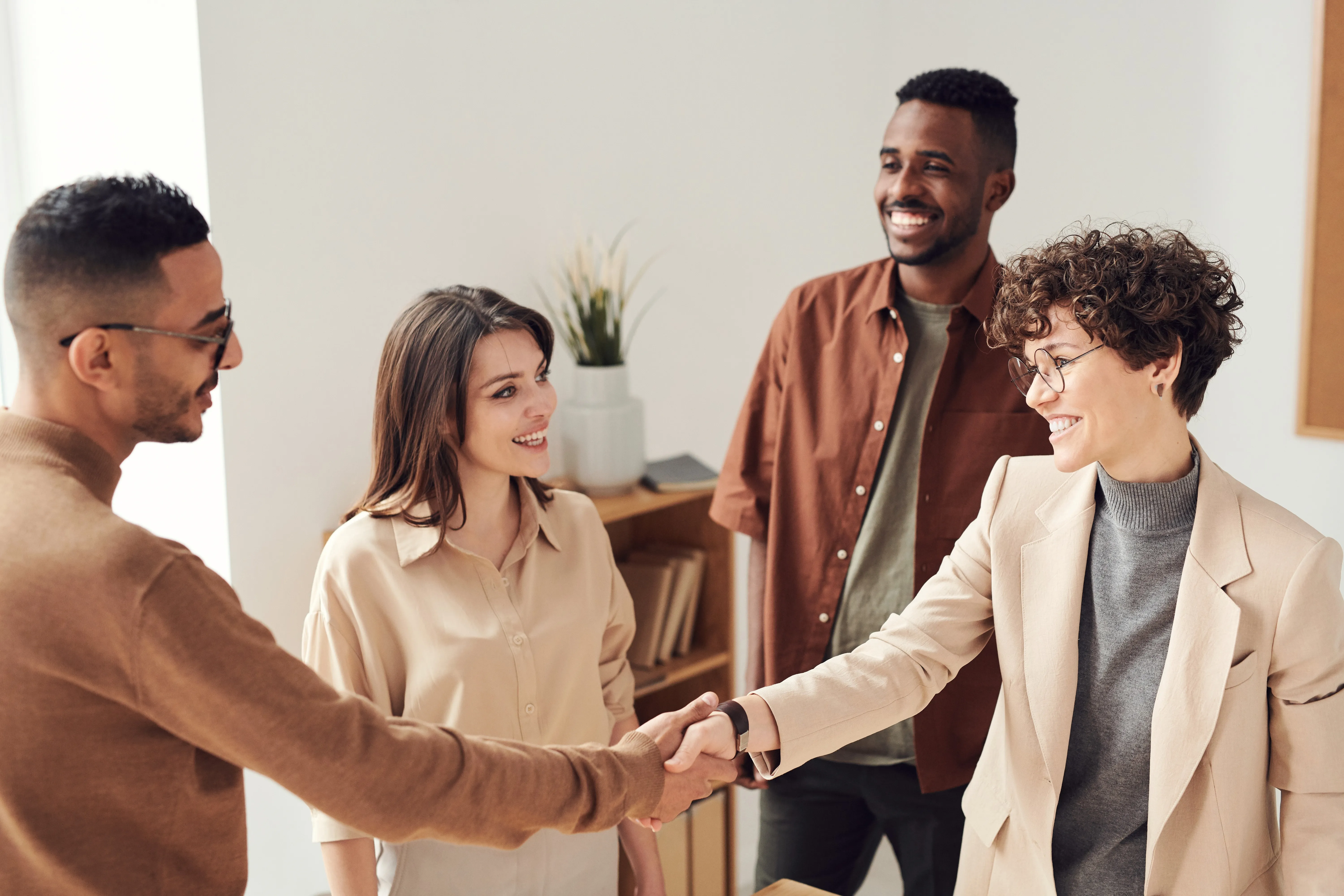 A man and a woman shaking hands with others looking on and smiling