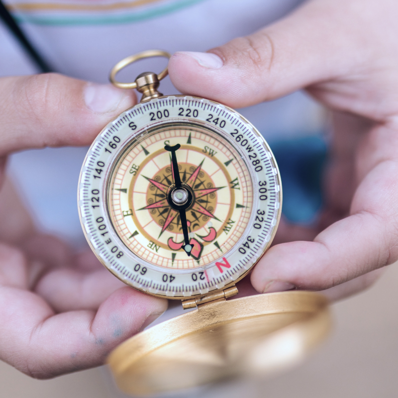 Hands holding a golden compass pointing North
