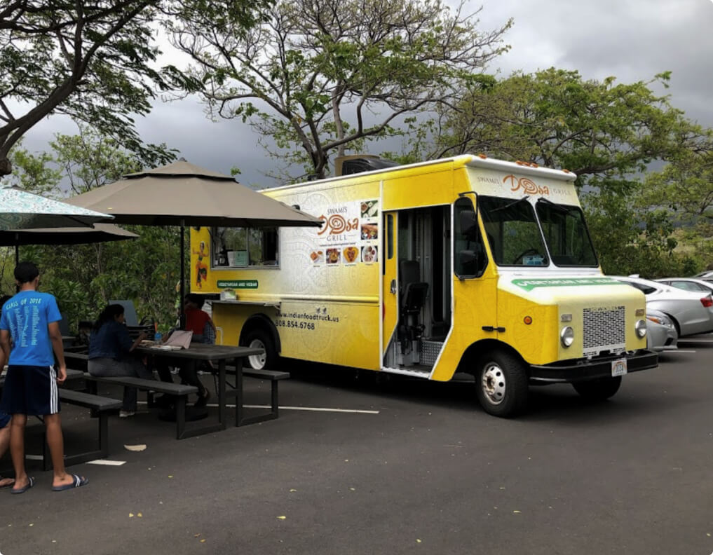 Big yellow food truck and people enjoying lunch 