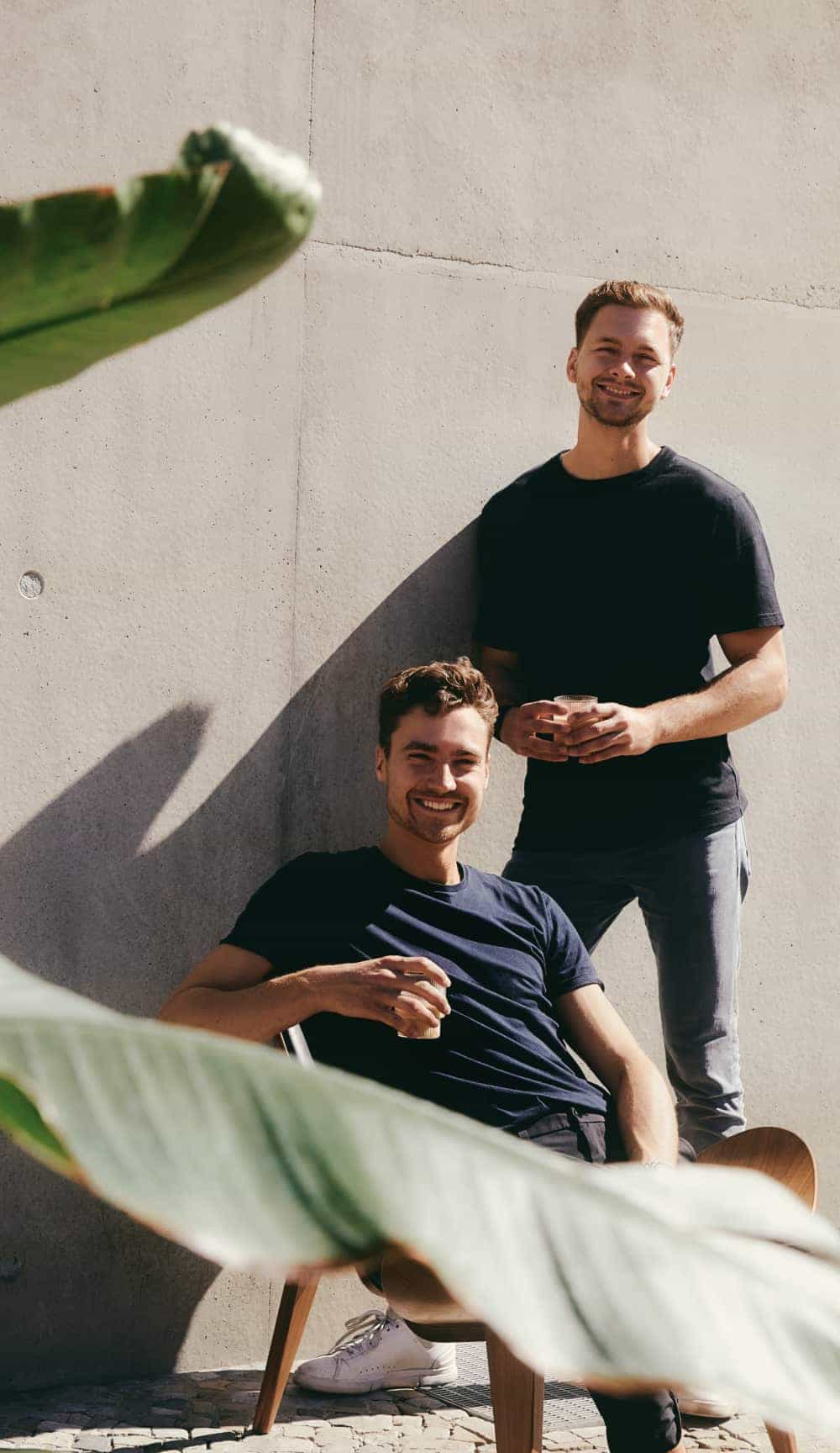 Two young men smiling with glasses of coffee in their hands