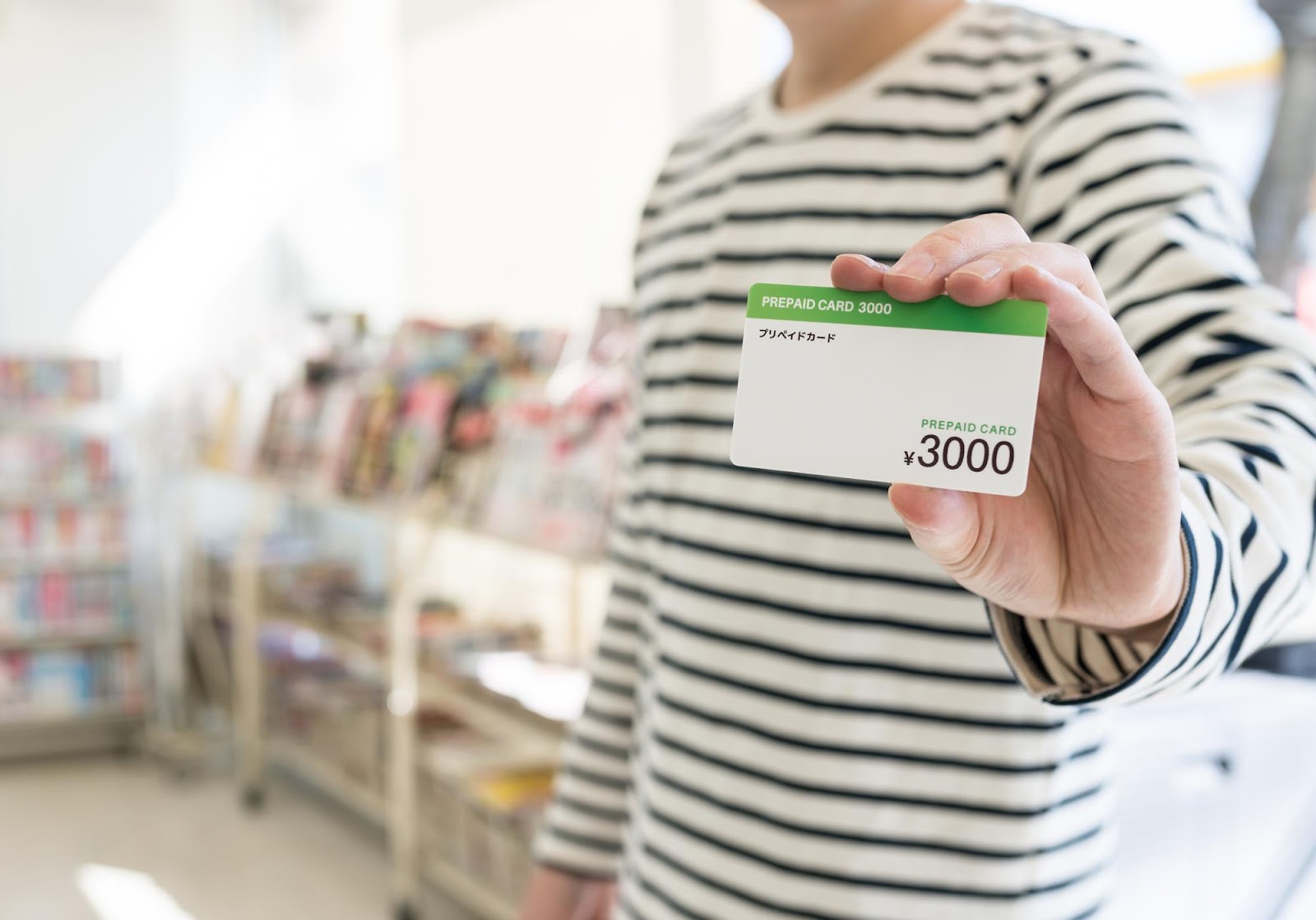 男性がコンビニで、3,000円相当のプリペイドカードを見せている様子