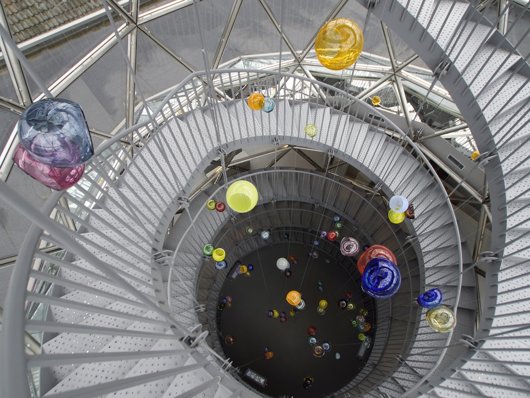 47 multi-colored glass globes by sculpture artist Michael Petry hanging from a spiral staircase at Glazenhuis in Belgium