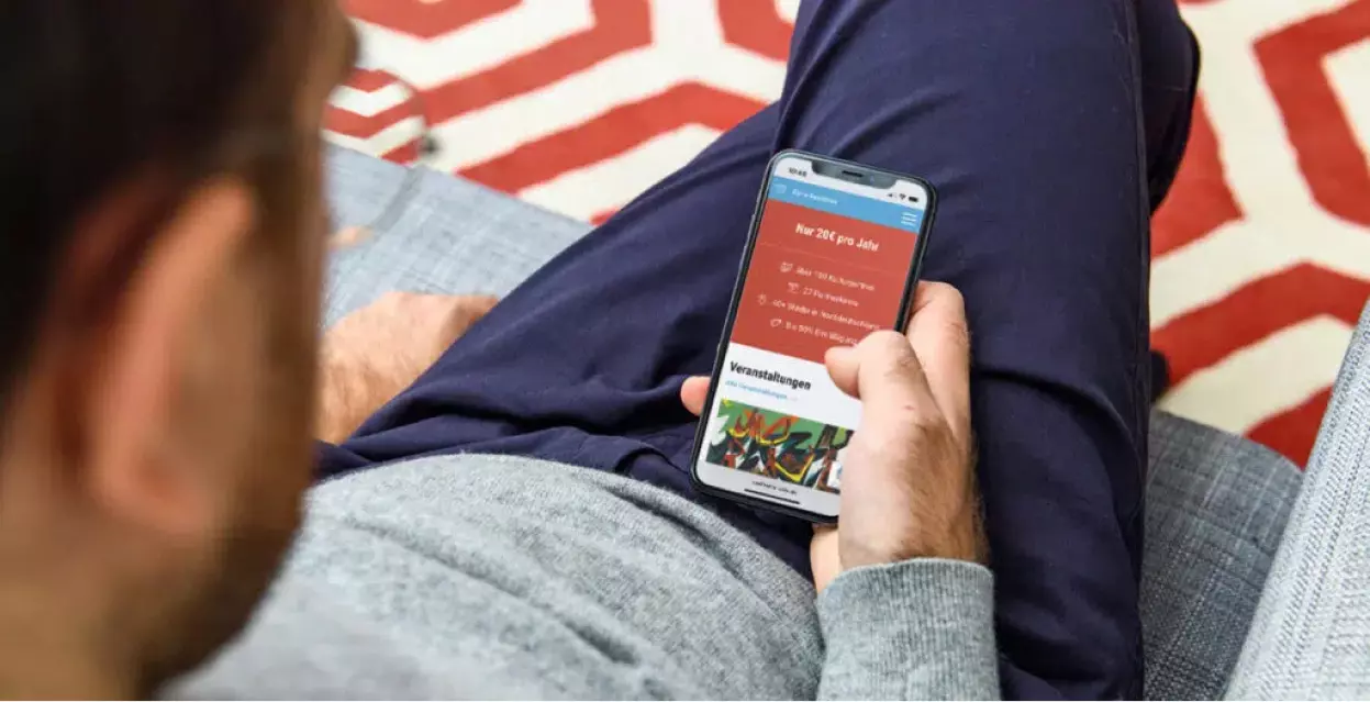Mann hält Smartphone in der Hand. Smartphone zeigt Startscreen der NDR Kulturkarte.
