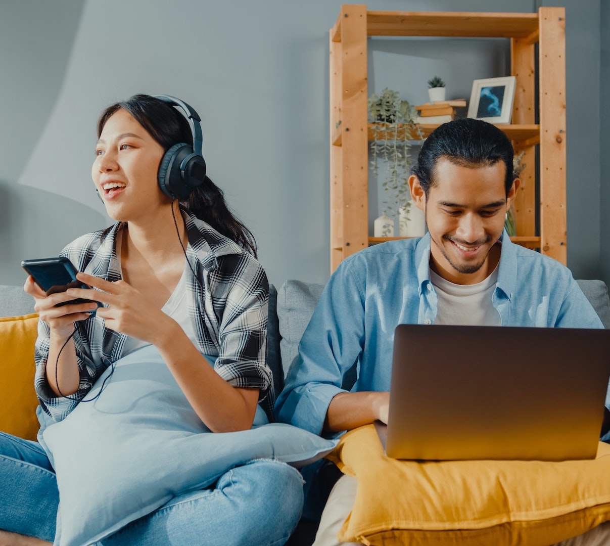 A couple using devices while sitting on a couch together