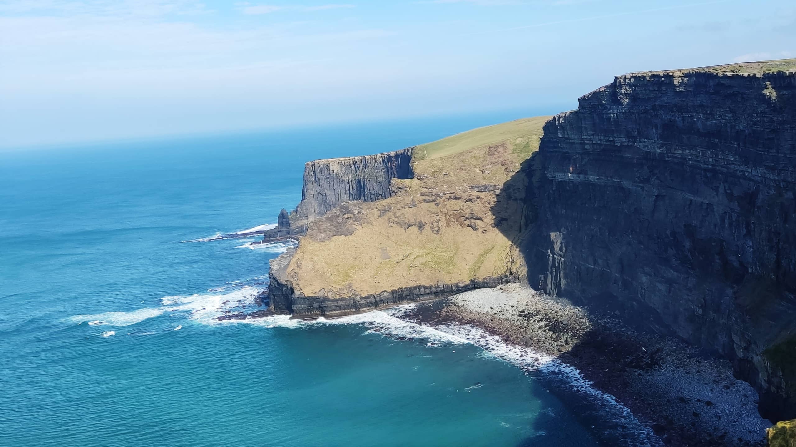 Irish cliff on a sunny day surrounded by deep blue ocean waters