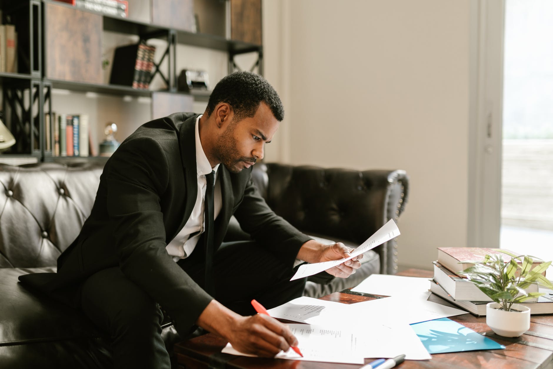 a man in a suit looking at documents on a coffee table