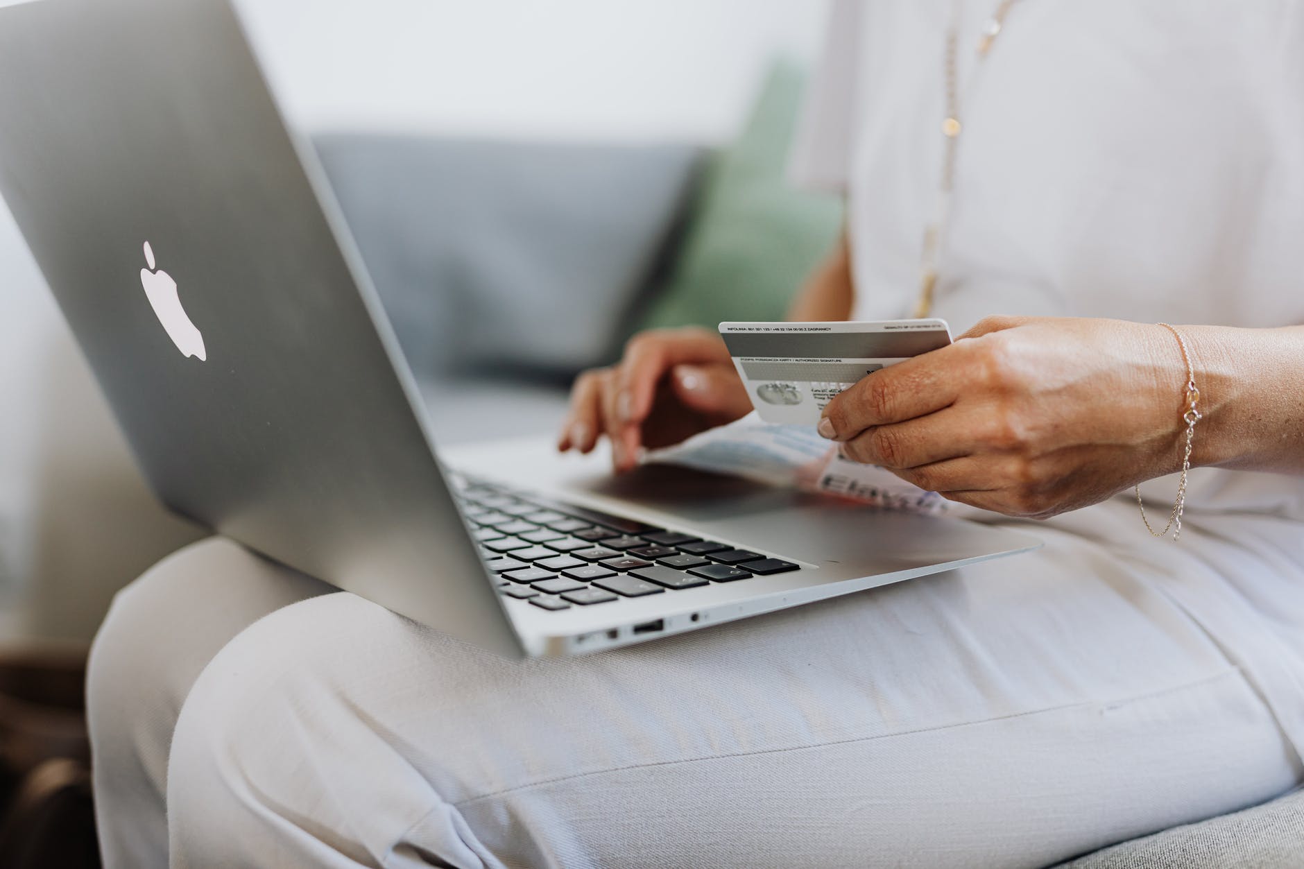 person using a macbook and holding a credit card