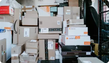 A large pile of stacked packages ready for delivery. The boxes are diverse in size, colour, shape and branding.
