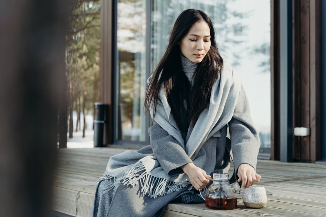 Photo of a woman on a porch drinking tea.