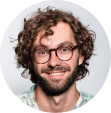 A young man with curly hair smiling.