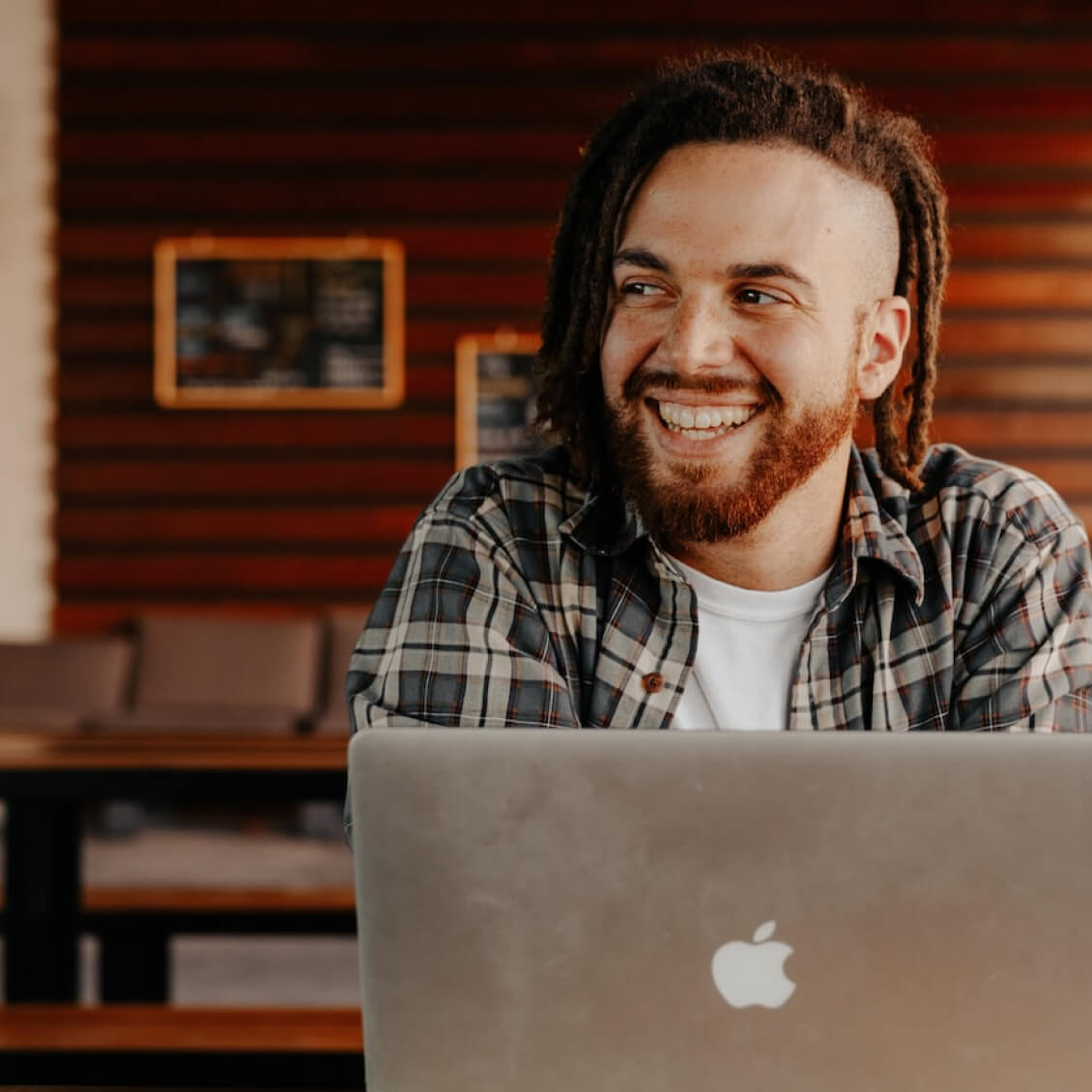 Young man smiling in front of his laptop.
