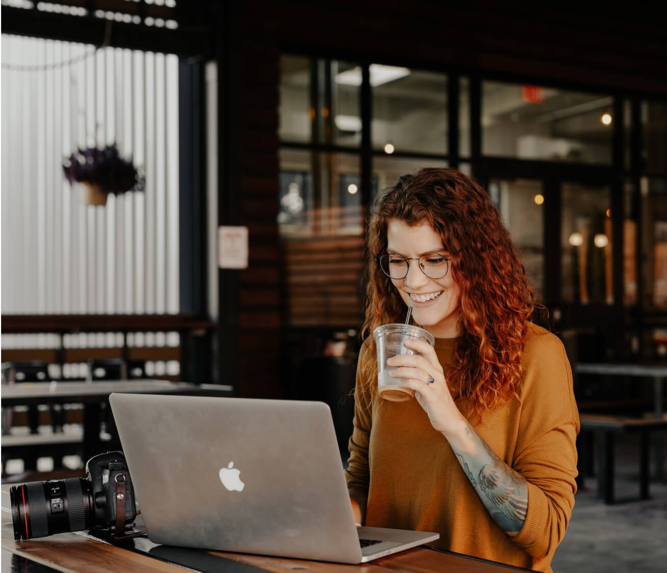 Woman drinking iced coffee in front her laptop in a local coffee shop. 