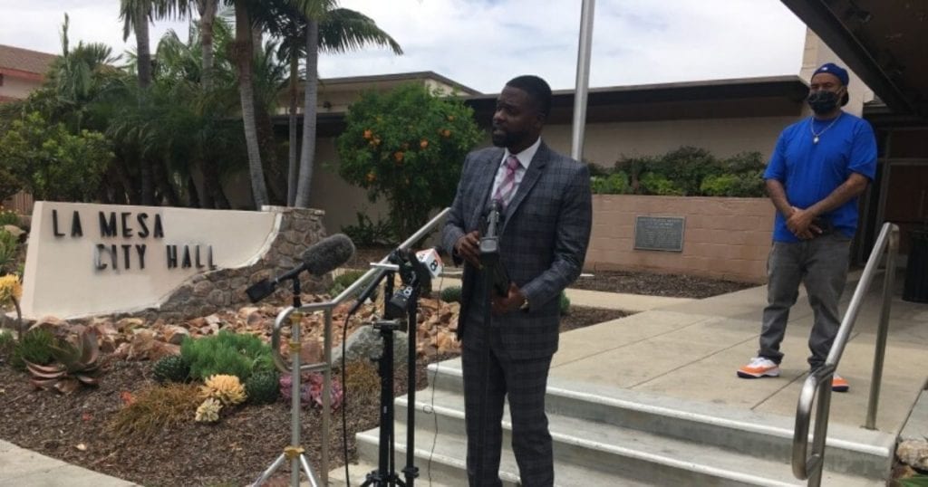 Standing at the back of a crowd of protesters against police brutality and racial profiling
