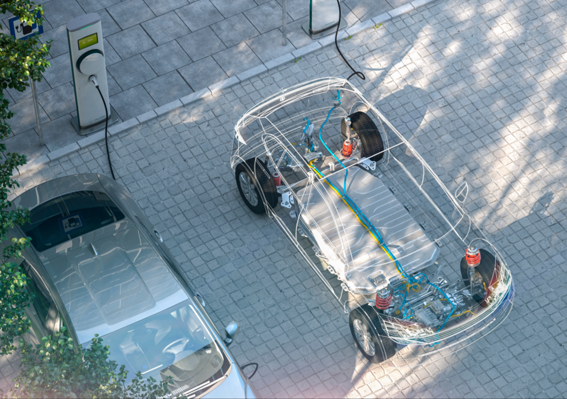 An electric vehicle parked at a charging station, with the car's battery and insides visible.