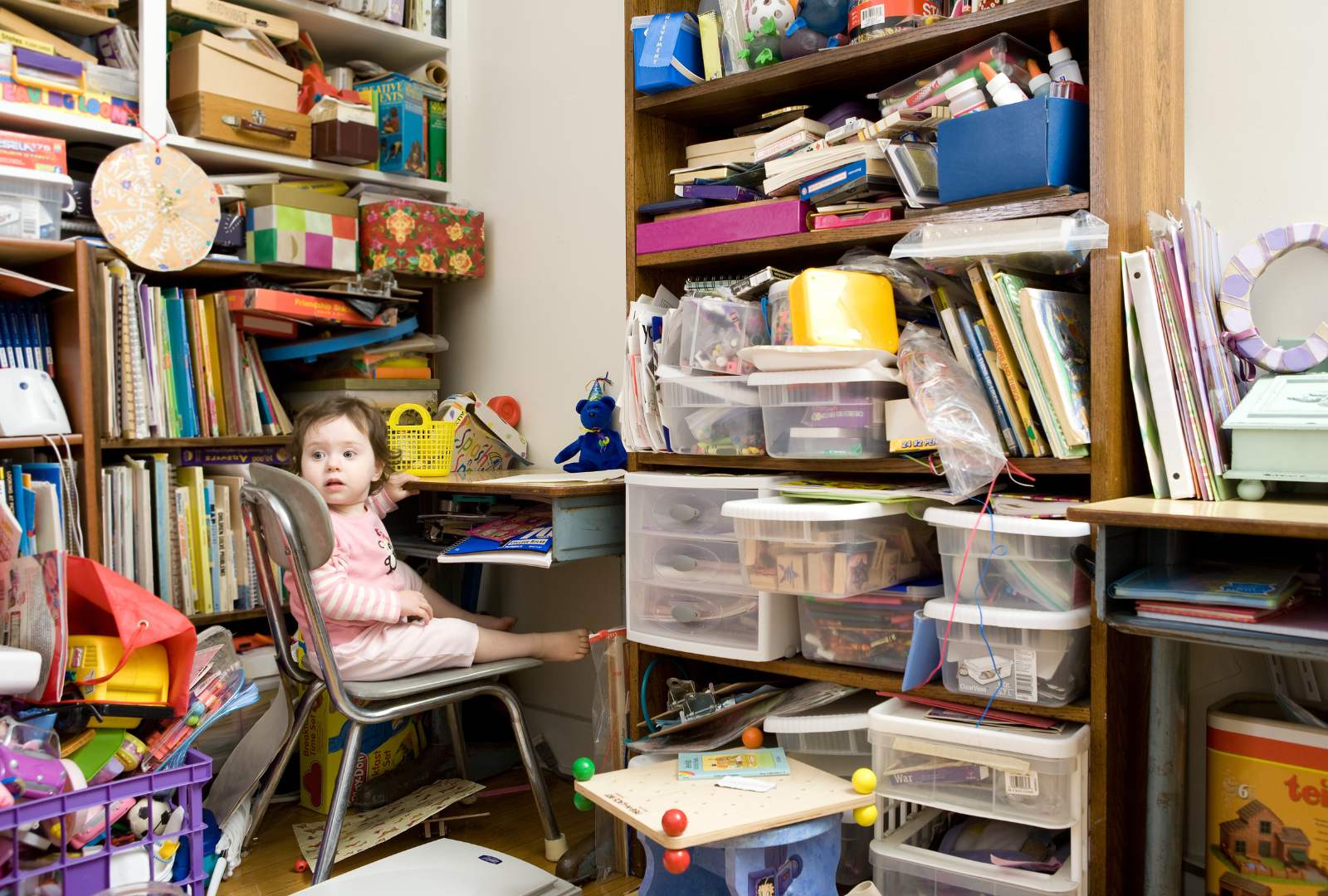 Toddler sitting in cluttered room at home