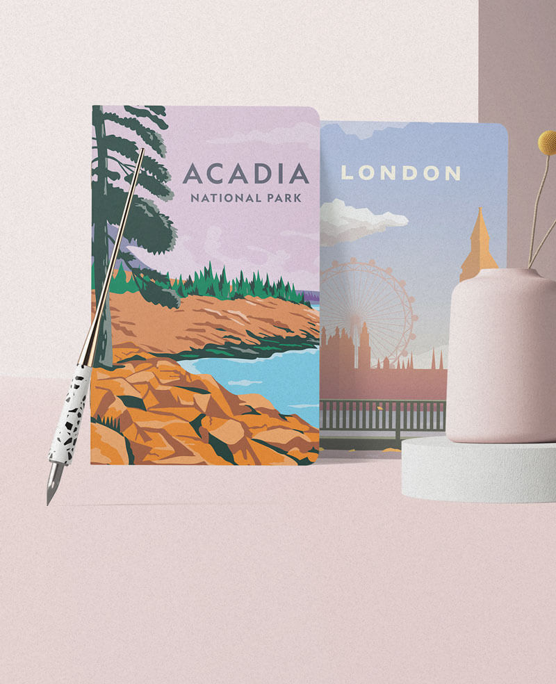 Two notebooks with Acada National Park and London city illustrated on it, leaned on a pink wall, next to a pink vase. 