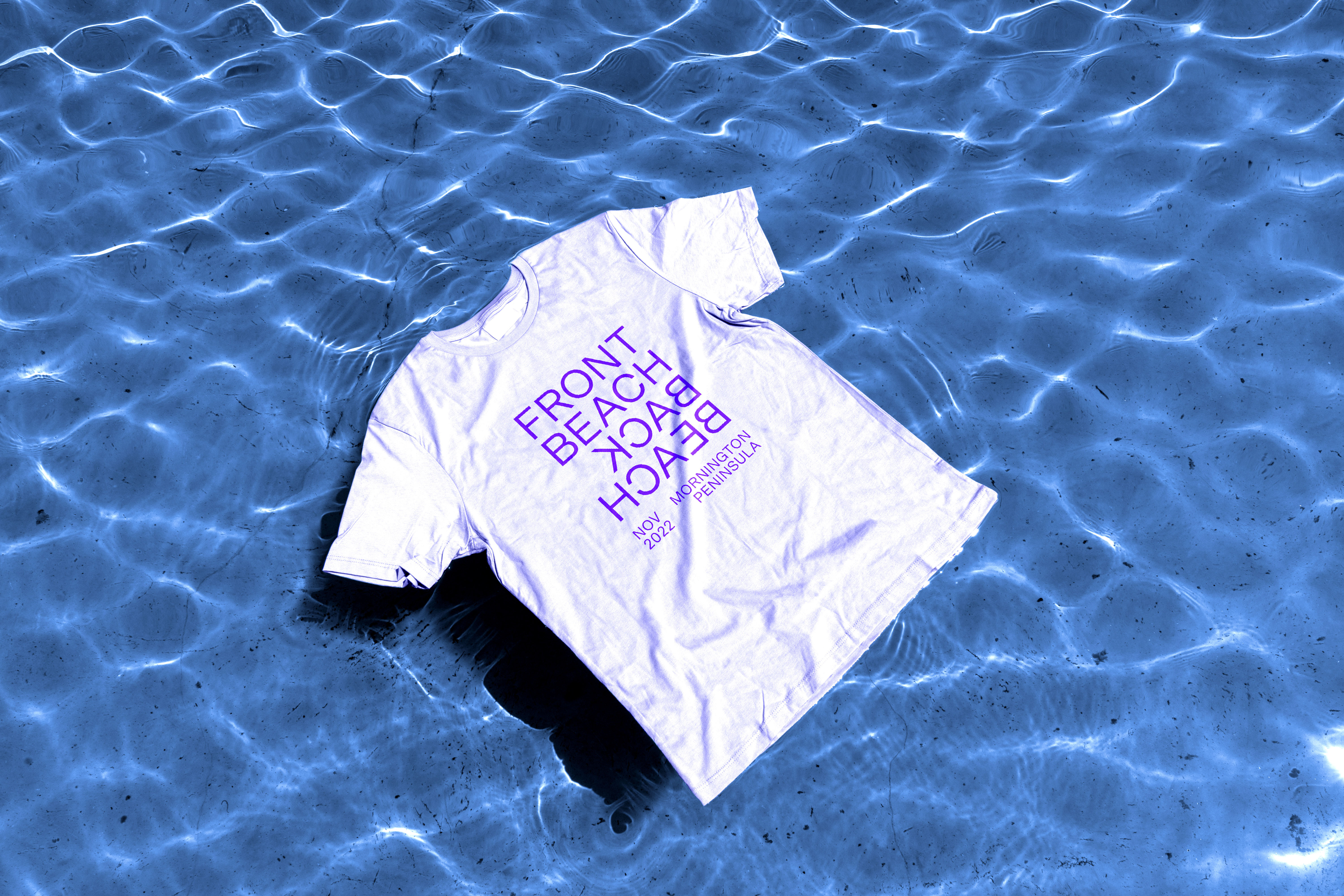 White t-shirt with Front Beach Back Beach logo sitting on top of water
