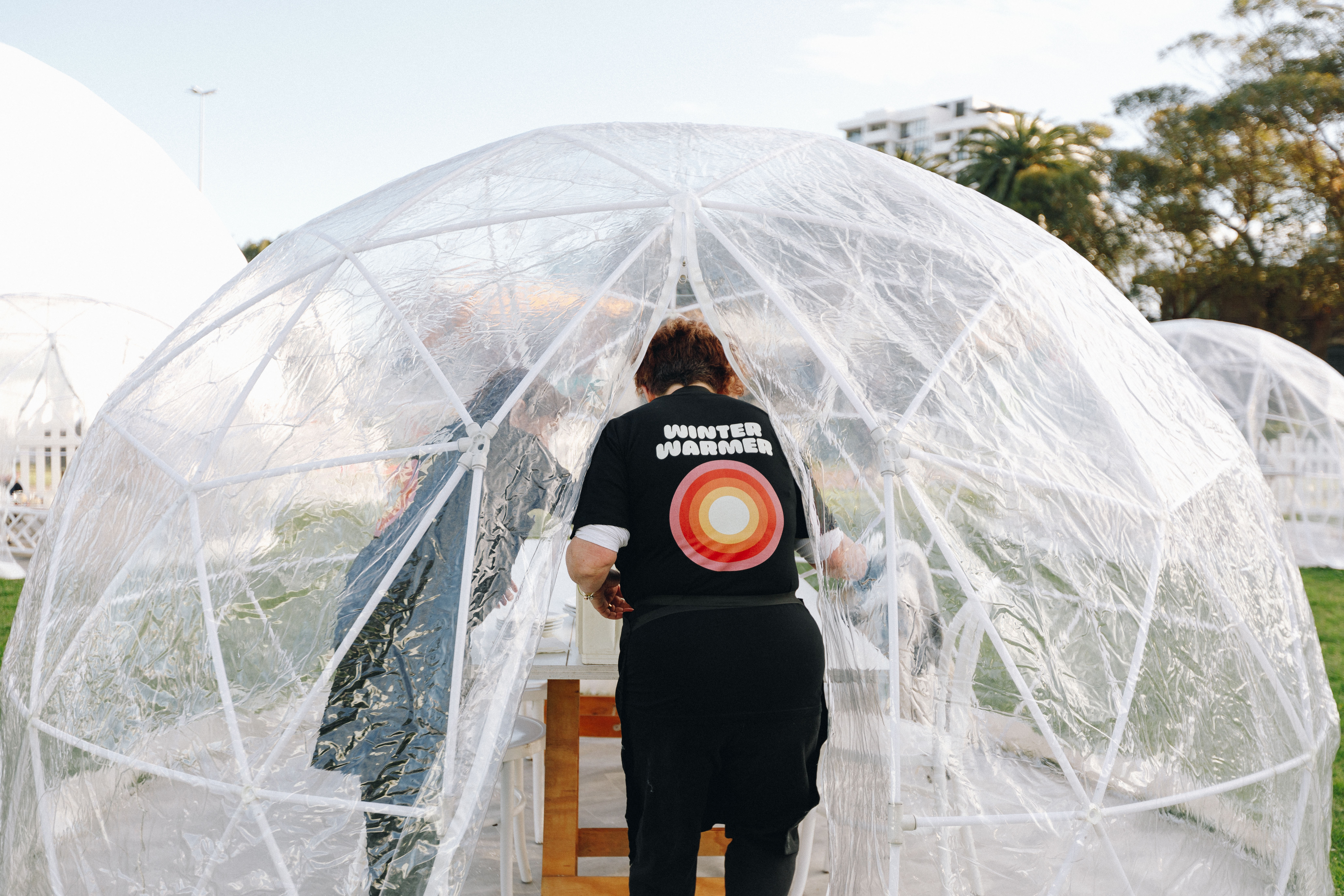 Photo of someone entering a plastic igloo with a t-shirt the says WINTER WARMER