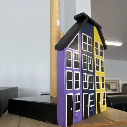 A paper towel holder decorated with a jelly bean row style house.