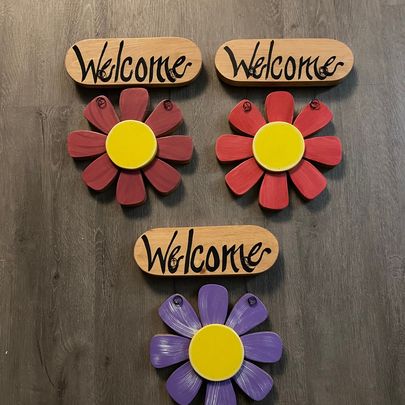Spring Flowers hanging from a sign that says "welcome".

