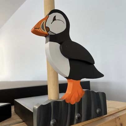 A paper towel holder decorated with a puffin.