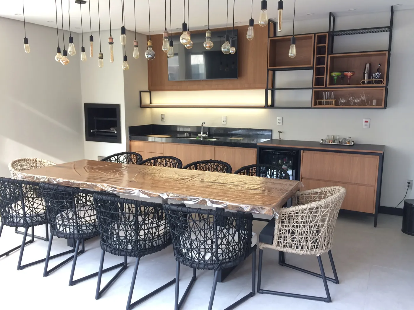 Imagem de cozinha, mesa rodeada por cadeiras brancas e cadeiras pretas. 