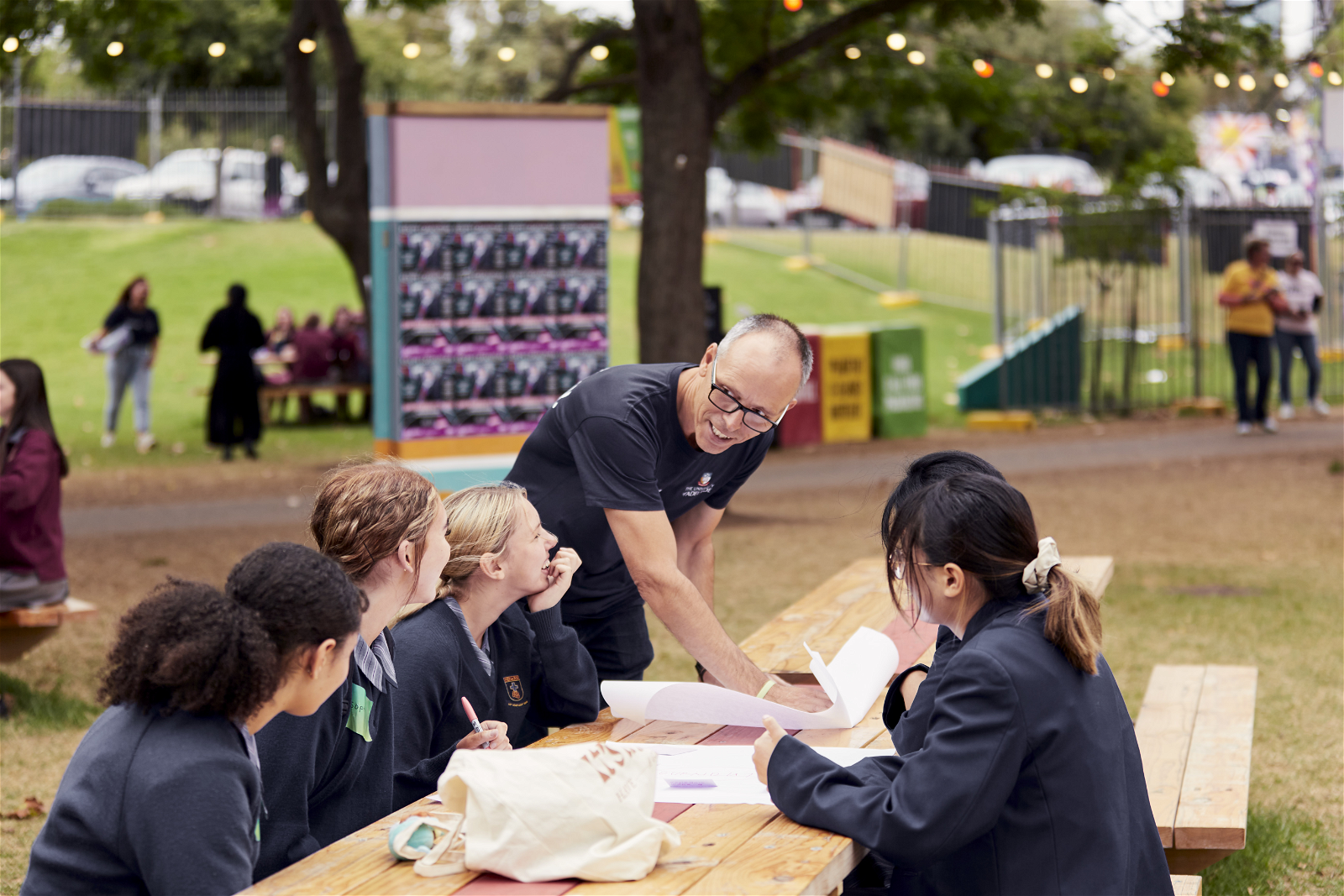 A group of female students engaging in an interactive workshop session outside in the Garden of Unearthly Delights, guided by a team member from University of Adelaide.