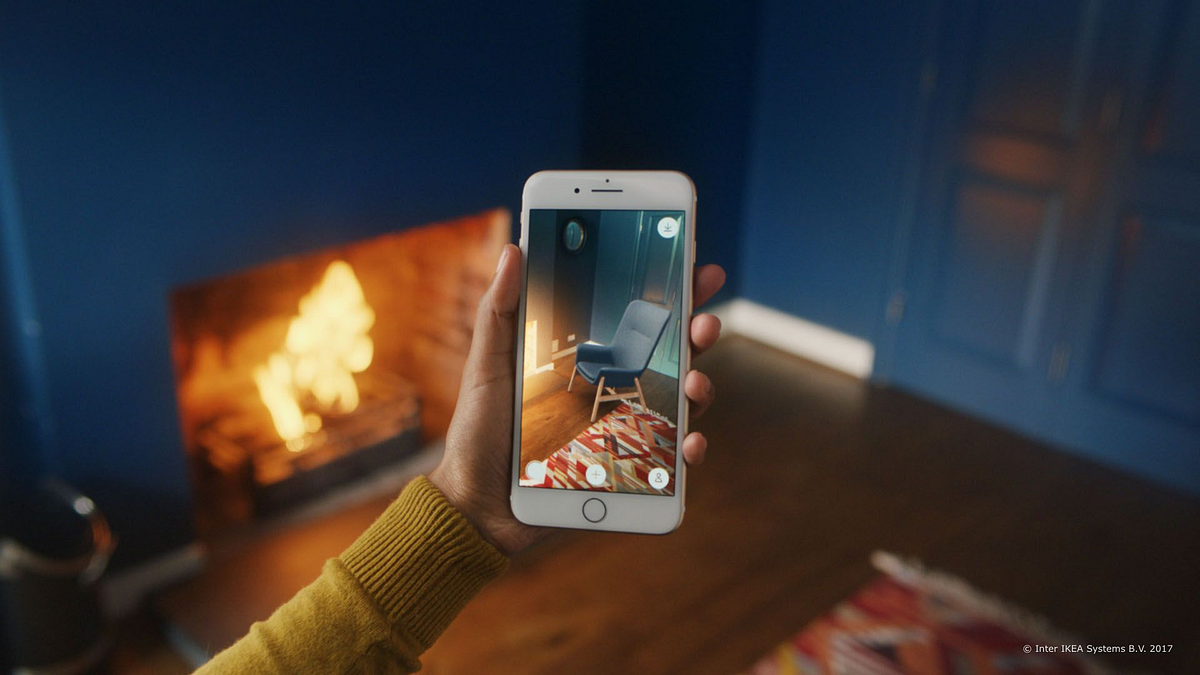 Person using AR on a smartphone to visualize a chair in a room with a fireplace in the background