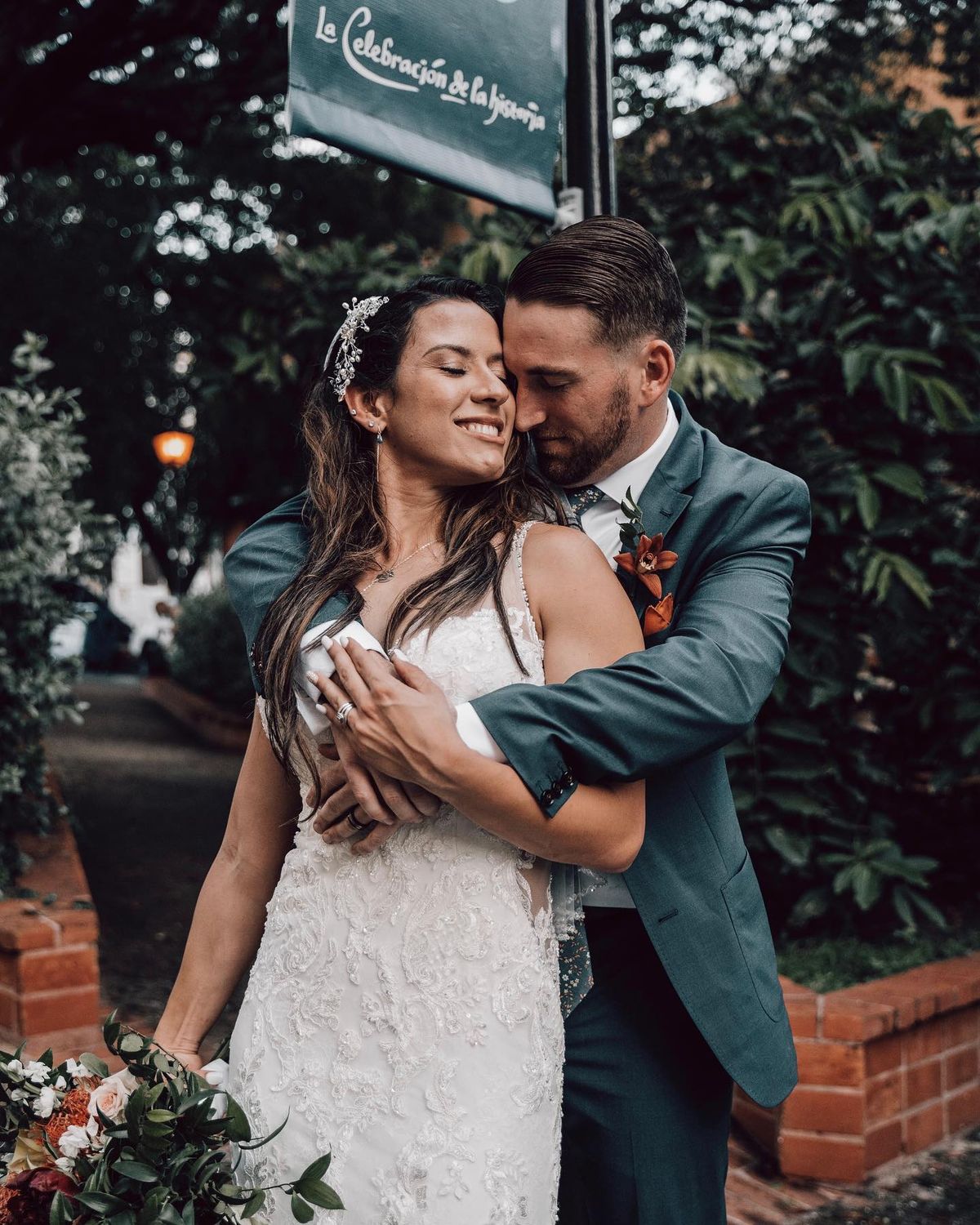Why Hire Wedding Videographer - Bride and groom sharing an intimate moment, with the groom whispering in the bride's ear, making her smile against a backdrop of lush greenery.