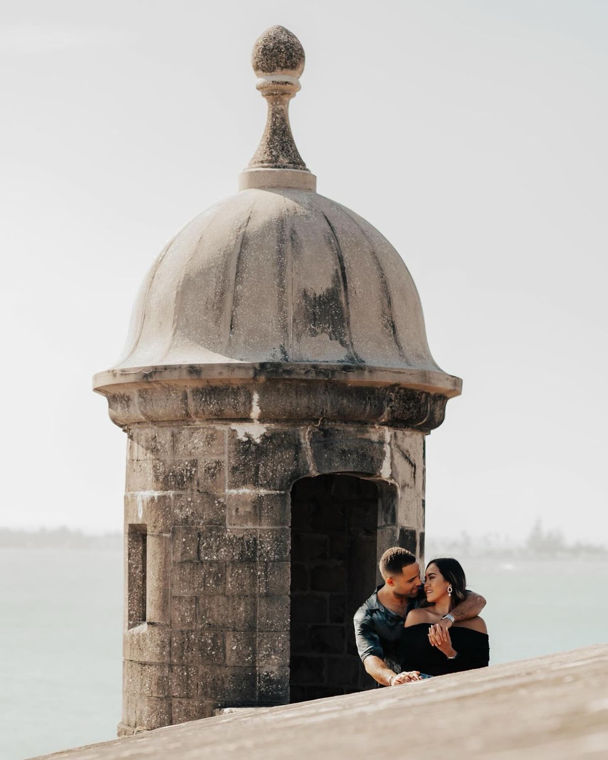 Orlando Wedding Photography Packages - A romantic couple embracing in a cozy nook of an old stone turret overlooking the sea.