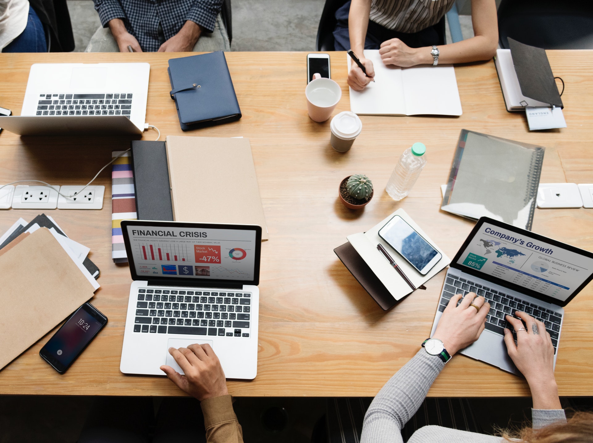 a group of people sitting at a table with laptops and phones