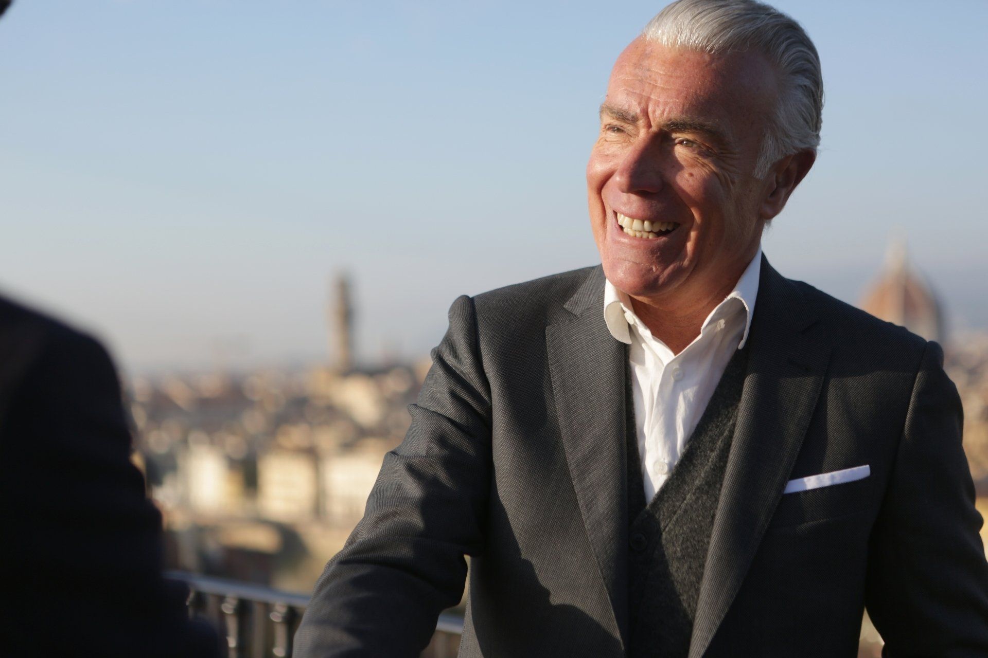 Smiling senior executive in business attire shaking hands outdoors, representing fractional management and leadership flexibility.