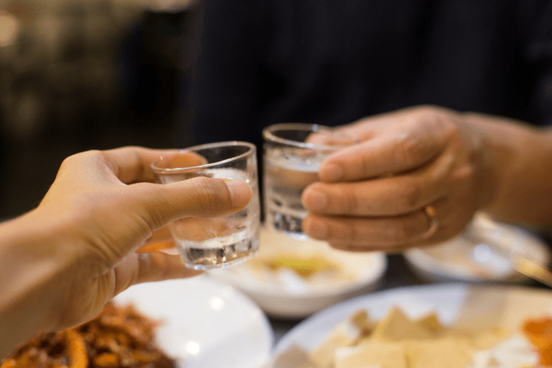 photo of two people holding glasses of soju in south korea